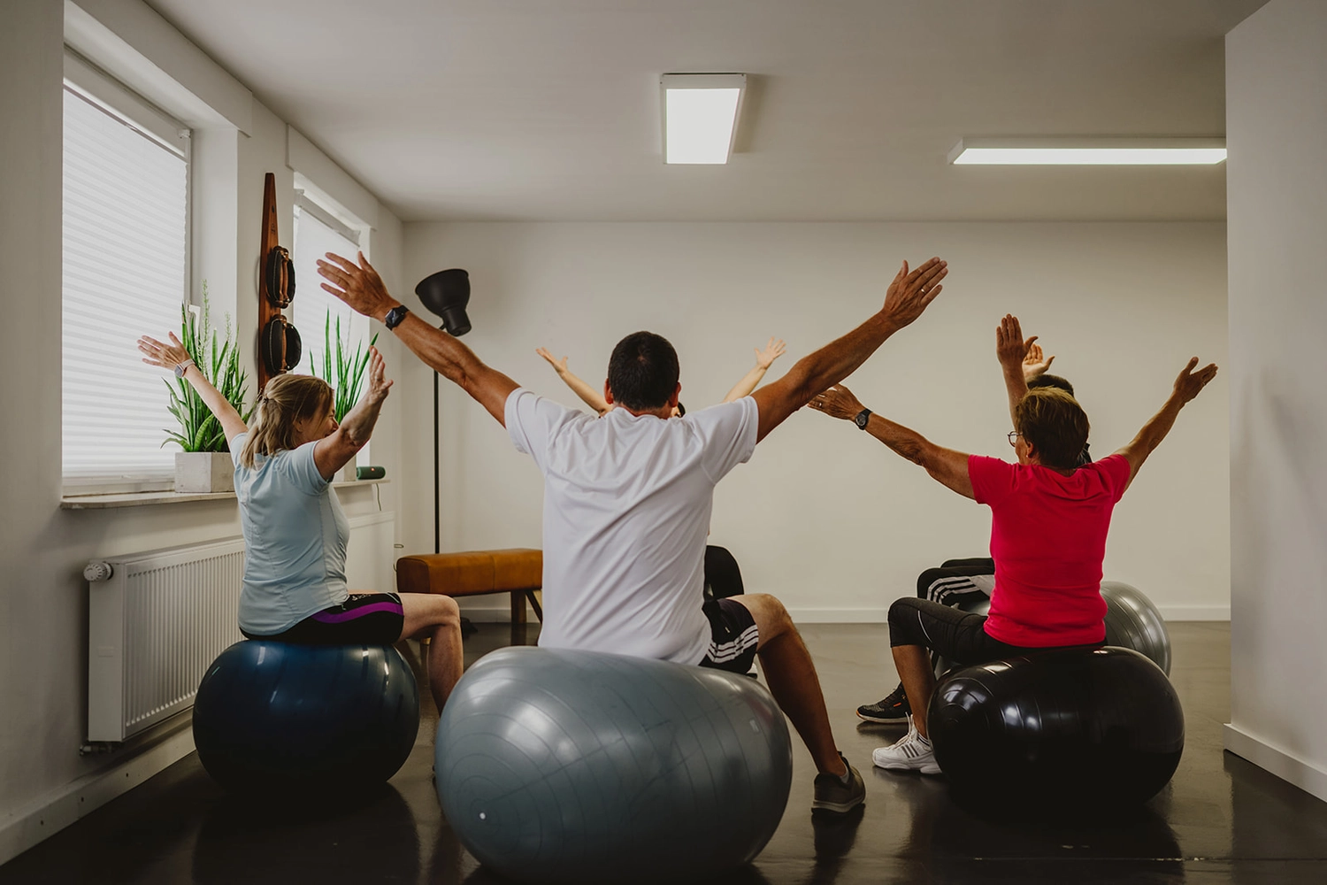 Körpermanufaktur - Physiotherapie. Osteopathie. Naturheilkunde – Dieses Bild zeigt einen Gruppenfitnesskurs mit Stabilitätsbällen, die häufig für Pilates oder therapeutische Übungen verwendet werden.